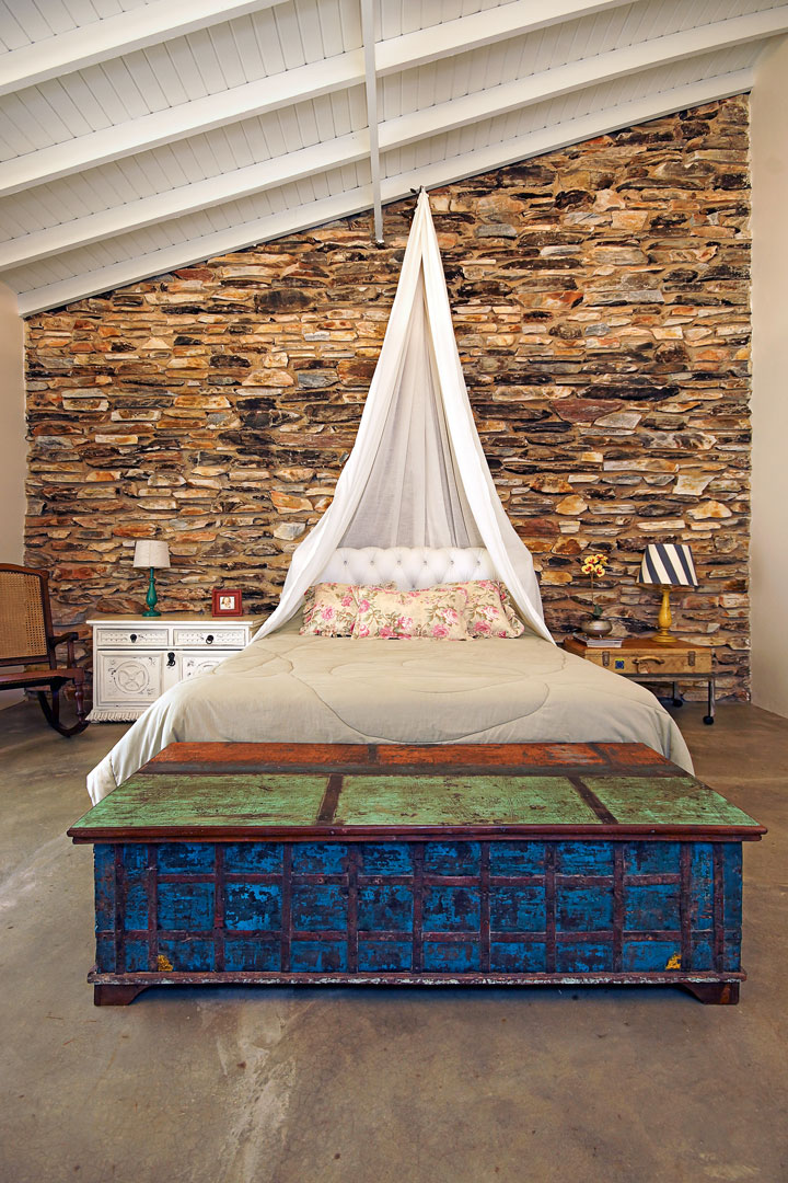 A suíte, com cadeira de balanço e baú oriental azul e verde (Ori Home Decor). O dossel sobre a cama evoca romantismo