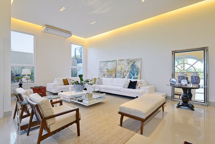 Um jardim privativo, o living espaçoso foi ambientado com móveis proporcionais, como os grandes sofás brancos (Breton Actual), almofadas coloridas (Anna Maria Decorações), tapete e poltronas (Aimar Móveis). O forro de gesso (AD Gesso) embute a iluminação e garante uma atmosfera mais acolhedora. A mesa preta junto ao espelho é da Mobiliarium Home.