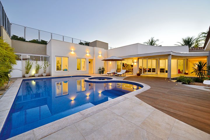 Na área de lazer com academia e sauna, a piscina sinuosa revestida com pastilhas Jatobá (Eco Portinari) conta com escada, prainha e hidrospa. Ombrelone e espreguiçadeiras da Mobiliarium Home. Toda a casa é automatizada e a iluminação é da Lumiarte.