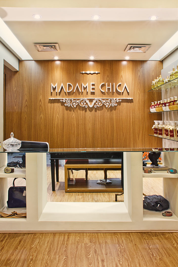 O painel de madeira ressalta a logo da loja. Estantes de vidro exibem com leveza os produtos para casa