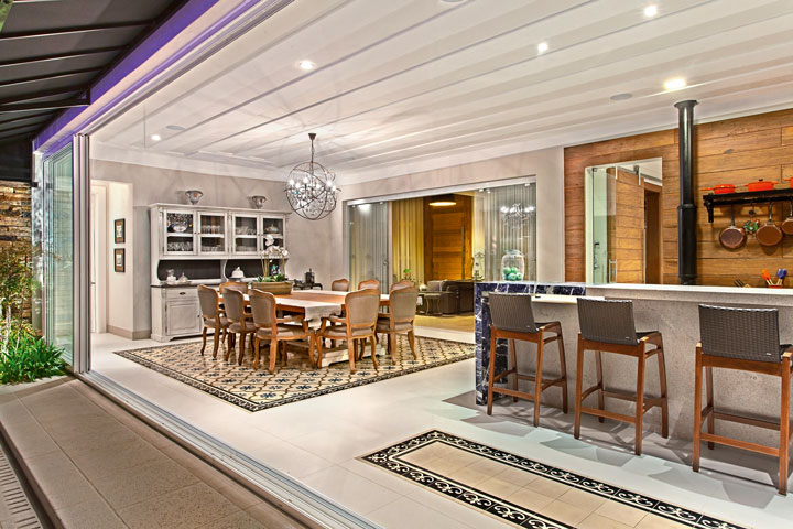 o espaço gourmet traz tapetes de ladrilhos hidráulicos Antigua em composição com o porcelanato da Portobello Shop. A mesa de madeira e guarda-louças são da Casa Malgga