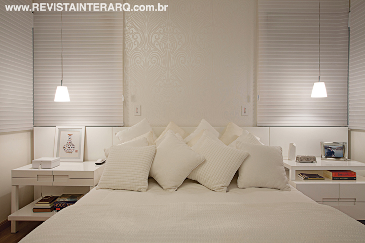 Delicada e relaxante, a suíte segue a proposta clean e apresenta papel de parede, enxoval (Decorações Casarão), móveis sob medida e persiana brancos. 