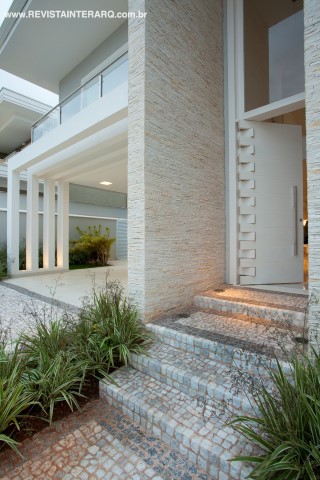 A fachada revela a personalidade contemporânea da arquitetura, finalizada por elementos clássicos, como o pórtico e as estruturas simétricas. Destaque para o jardim com espécies tropicais e para a porta de entrada pivotante em laca branca e com painel de vidro (Carvalho Madeiras). 