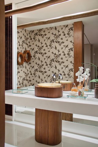 O lavabo é único, com a cuba em ônix iluminado (Marmoraria Alvorada) sobre tora de madeira (Mendo Barreto) na bancada em Nanoglass (Marmoraria Alvorada)