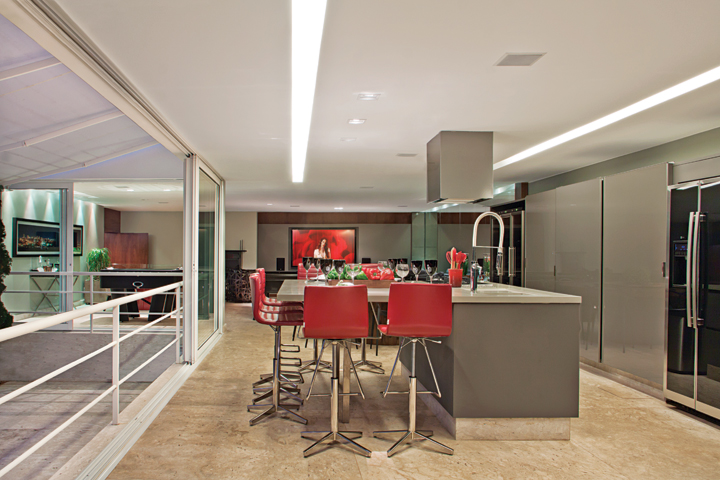 A bancada em Silestone, banquetas Classica Design (Quadra) e os armários em laca (Ornare) estão sempre prontos para os eventos gastronômicos. O piso é em mármore Bege Bahia Levigado. Toldos da Hunter Douglas, da loja Finestri