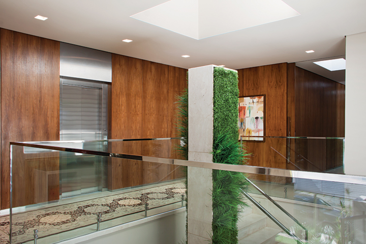 Um jardim vertical acompanha todo o pé-direito da casa até a altura da circulação da ala íntima, no segundo pavimento. O guarda-corpo de vidro é da Talentus Esquadrias 
