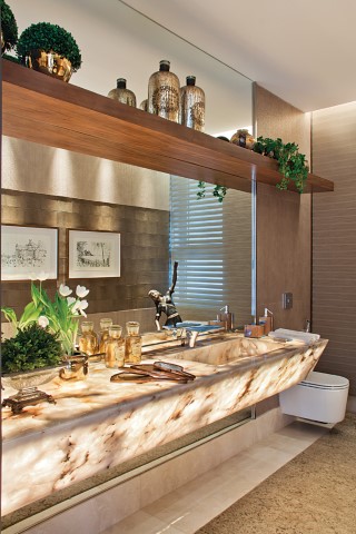 O lavabo, com bancada em ônix iluminado e monocomando Hansgrohe (Vallori) 