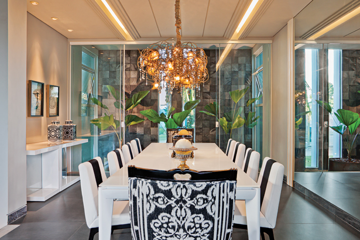 A sofisticada ambientação do jantar tem como moldura o jardim interno com a parede com pedras Hitam, da Palimanan (Vallori). Sob o lustre Scatto (Dessine Iluminação), mesa branca da Quadra Design e cadeiras da Artefacto