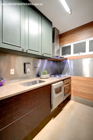 A cozinha foi revestida com madeira, aço inox e, nas gavetas, papel de parede de couro de crocodilo no tom vinho (Wood Design). A bancada em Corian foi executada pela Granipedras