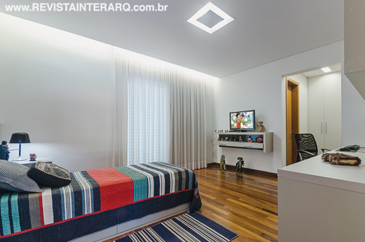No dormitório do filho, o enxoval colorido dá bossa ao ambiente com piso de madeira e armários sob medida