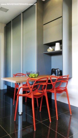 A cozinha, a cor mais sóbria dos armários planejados (Kitchens) ressalta o vermelho vibrante das cadeiras Masters, da Kartell (Jackie Móveis). O piso em granito preto (Marmoraria São Jorge) é de fácil manutenção. As portas são da Rossi & Sbrogio. As portas são da Rossi & Sbrogio e as fechaduras, da Casa das Portas. Metais da Casa dos Construtores