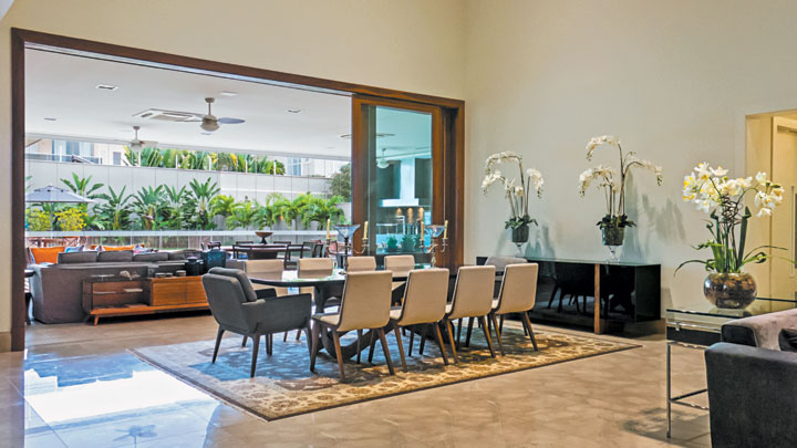 A mesa em laca preta (Visual Q) compõe com as cadeiras (Decorativa) e tapete claro (Gallery Antiqua). Sobre o buffet (Decorativa), arranjos florais da Perfil Casa. Todo o piso social da casa é em mármore Botticino (Stone Center)
