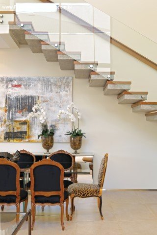 A leveza da mesa de jantar em cristal da Jacqueline Terpins e do aparador espelhado (ambos da Jackie Móveis) complementa o ar clássico das cadeiras de estilo. Toda casa foi automatizada pela Connect Home. O piso é em porcelanato da Portobello Shop