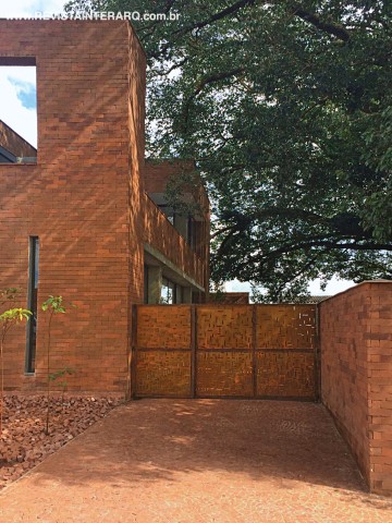 O portão em aço corten enferrujado, desenhado pela arquiteta, completa a composição