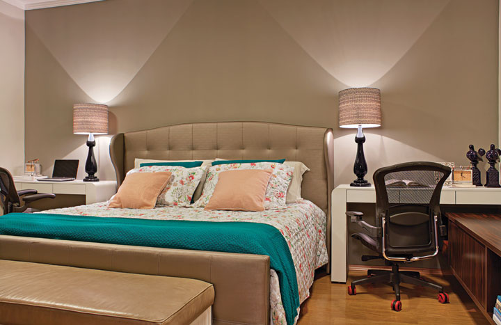 A suíte é um refúgio para relaxar, com iluminação intimista, paredes cinza e enxoval da Trousseau (Libélula Home). Emoldurando a cabeceira em capitonê, a marcenaria planejada e as cadeiras Herman Miller (Perfil Office) acomodam espaços multifuncionais para o casal. Os abajures são da Perfil Casa