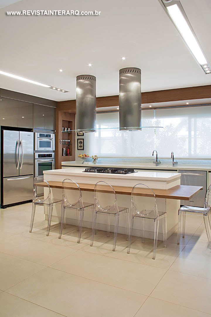 A cozinha gourmet, os armários planejados e as bancadas em Corian branco (tudo da Kitchens) compõem com as cadeiras Victoria Ghost da Kartell (Jackie Móveis) junto ao balcão de apoio