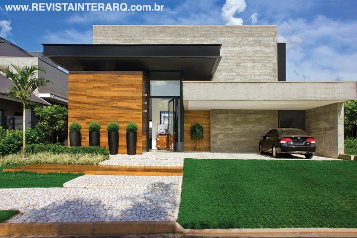 Uma “caixa” de vidro e esquadrias pretas (Projesp) forma o hall de entrada da casa, decorado com cômoda bombê e telas contemporâneas (ambos Roberto Chaim). A arquitetura com volumes e linhas retas foi finalizada com madeira, aço e concreto. No piso, o petit-pavet branco contrasta com o verde do paisagismo assinado pela Verdeplan