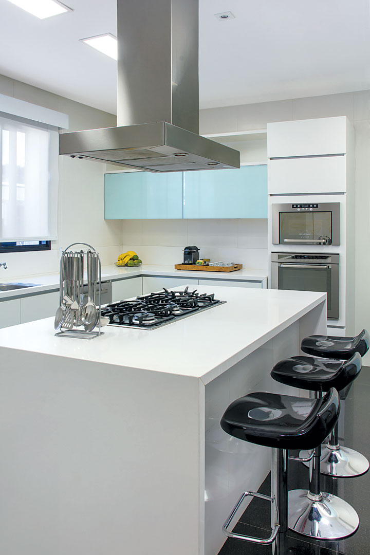 Bancada em Caesarstone (Stone Center), azulejos brancos (Portobello Shop) e armários planejados claros resultaram em uma cozinha clean e agradável. Coifa em inox da Refrigeração Araçatuba e iluminação da ViaLight