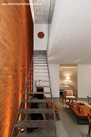O térreo abriga um ambiente integrado com uma suíte com dois banheiros, cozinha gourmet e living. Todo o piso foi revestido com pastilhas de vidro cinza da Colormix. Nos degraus vazados da escada em aço corten enferrujado, com design exclusivo (foto maior), a iluminação pontual projeta luz e sombras no teto e no piso