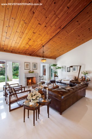 Com estar com lareira em mármore Carrara (Marmoraria Lapidare) e jantar para 10 pessoas, o décor mescla móveis novos, como o sofá Chesterfield, com peças de estilo e de antiquários, como os lustres em bronze e alabastro e a mesa inglesa