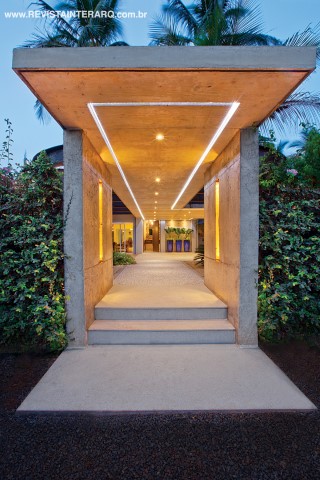 A entrada social foi totalmente renovada e reflete a personalidade sofisticada e empreendedora dos novos proprietários. No espaço, materiais como aço corten, concreto armado aparente, madeira e granitos (Marmoraria Lapidare) se aliam aos traços arquitetônicos arrojados para conferir um ar bucólico e contemporâneo