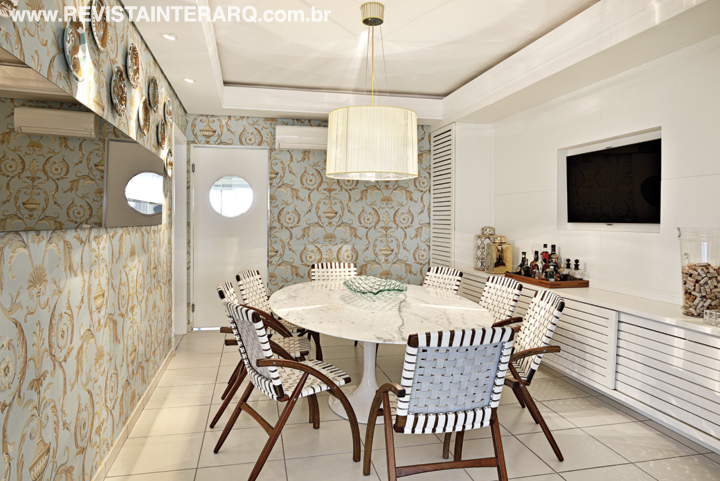 Leve e charmosa, a sala de almoço foi vestida com papel de parede arabescado, que valoriza o branco da mesa Saarinen, cadeiras em tiras de couro Flexa Carlos Motta (Jackie Móveis) e lustre italiano (ViaLight). O espelho é da Adresse (Jackie Móveis), buffet da Nativa Movelaria e pratos do artista plástico Sylvio Viana