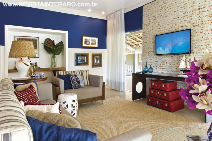 O acabamento em lambri branco e as cortinas de linho formatam o mais puro estilo náutico junto à coleção de barcos na decoração