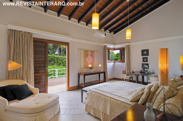 Uma das suítes, com o aconchego do teto de madeira e da paleta neutra. Luminárias da ViaLight 