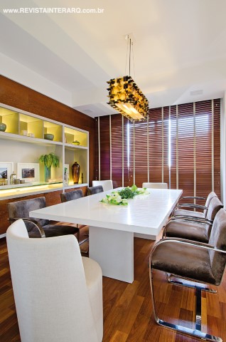 As persianas de madeira Hunter Douglas (Ateliê Revestimentos Roberto Cervellini) e a mesa de mármore branco Thassos replicam o jogo de cores do móvel projetado pelo profissional, assim como as cadeiras claras Erea e as poltronas Bruno de veludo escuro. O lustre é de pastilhas de chifre. Luzes da estante da Ilumilight