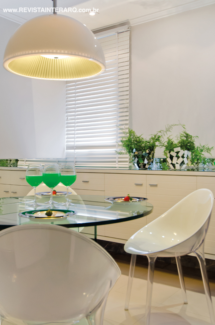 A cozinha é toda branca, com piso em mármore e cadeiras da Kartell