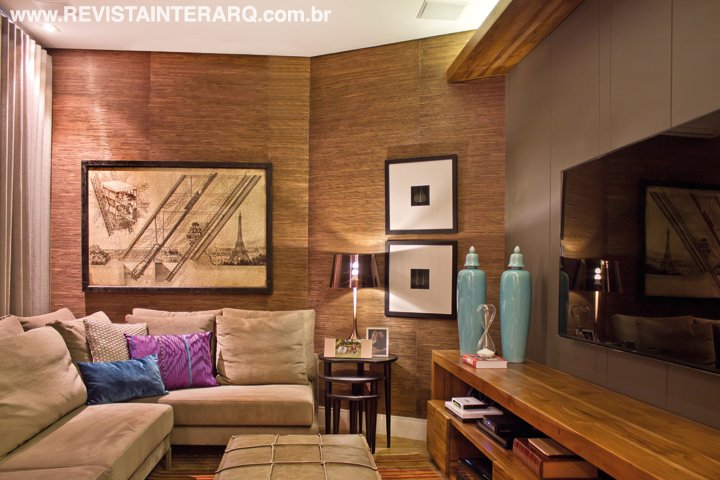 O papel de parede de palhinha envolve a decoração do home theater, conferindo beleza e melhor qualidade acústica. A iluminação indireta reforça a ideia de relaxamento e descontração