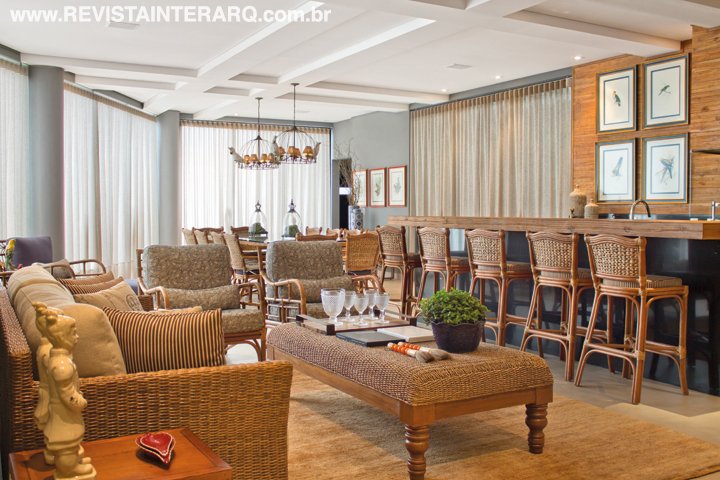 Palco das festas e encontros da família, a varanda gourmet esbanja charme com as luminárias estilo gaiola e móveis de madeira de demolição e fibras naturais. Quando abertas, cortinas e portas de vidro integram a área da piscina, ambientada com móveis de alumínio e estofados com tecido náutico. O projeto arquitetônico da casa é de Karina Winter