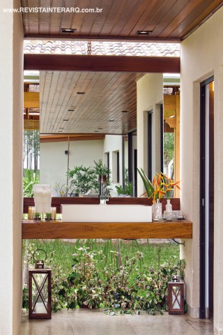 O interessante efeito visual do lavabo, com aberturas nas laterais do espelho (Marmoraria e Vidraçaria Avenida) e bancada flutuante em madeira com cuba em Caesarstone (Galeria das Pedras)