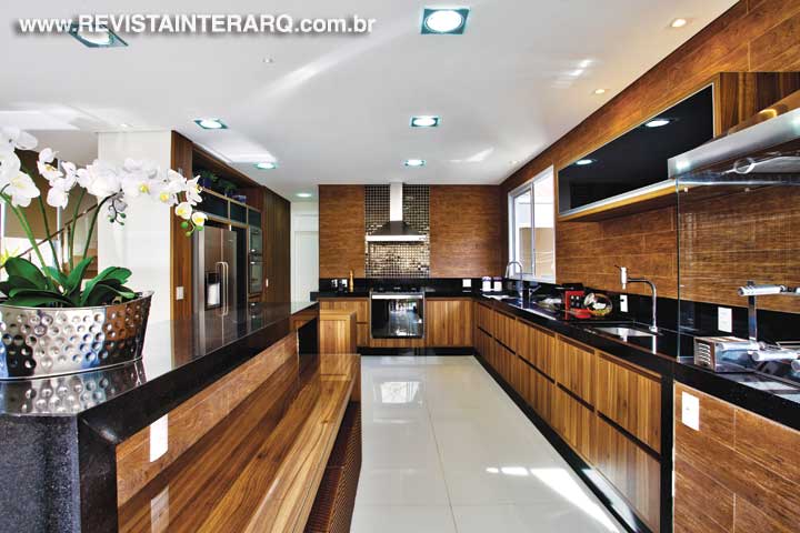 Na cozinha gourmet, a atmosfera receptiva foi conseguida com a combinação do porcelanato amadeirado nas paredes e armários no mesmo padrão