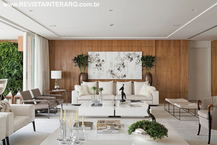 Paredes revestidas em madeira Nogueira valorizam ainda mais o décor claro e elegante. Soluções inteligentes foram incorporadas à execução da obra, como a automação dos ambientes, além de portas e painéis invisíveis 