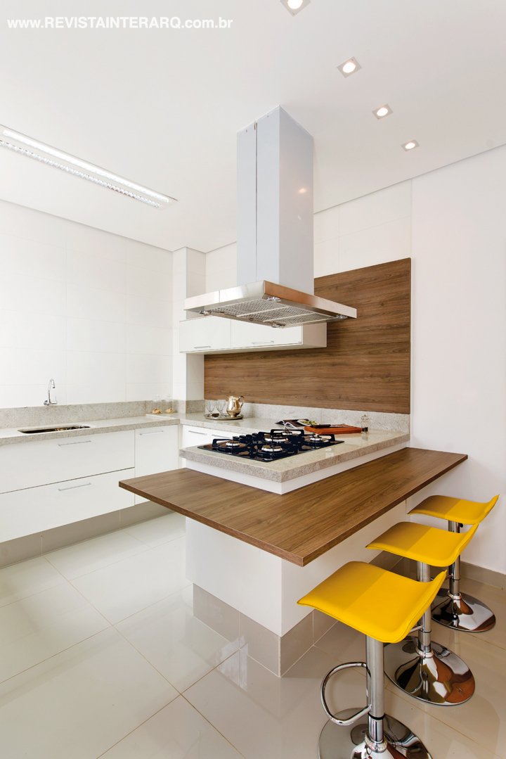 Na cozinha planejada (Dell Anno), a ilha central convida ao bate-papo entre anfitrião e convidados e as banquetas amarelas (Espaço Moderno) finalizam o ambiente com um toque contemporâneo. Coifa em inox e cooktop da Coifas e Coifas