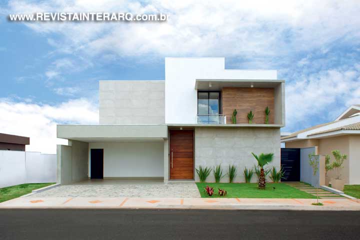 A linguagem arquitetônica com linhas retas e o efeito de concreto aparente conferem à residência um ar contemporâneo. No piso superior, o detalhe em porcelanato amadeirado ressalta a sacada