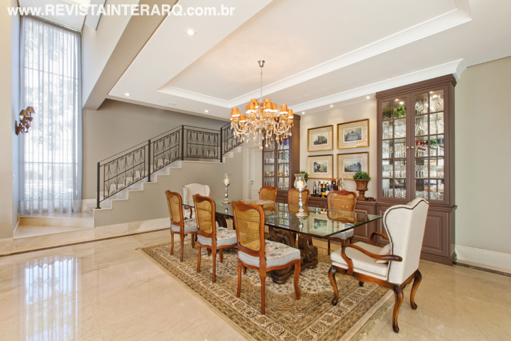 As cristaleiras desenhadas pelas profissionais acomodam as taças sem ocupar muito espaço na sala de jantar. Herança de família, a mesa de vidro completa a cena com cadeiras com encosto de palhinha, poltronas estofadas (Sierra Perfil Casa), tapete oriental e lustre clássico