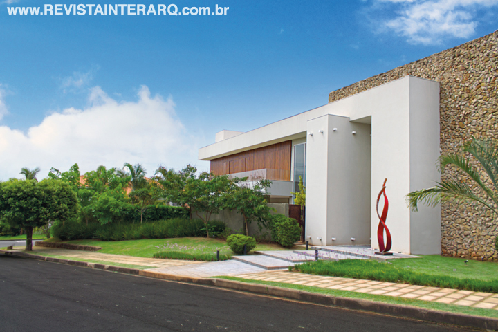 Canteiros com alho-social foram posicionados ao longo do acesso social para incorporar flores a esse trecho. Além das plantas, o paisagista sugeriu a utilização de uma escultura em ferro, do artista Romildo Cardozo, para acompanhar a verticalidade da porta de entrada