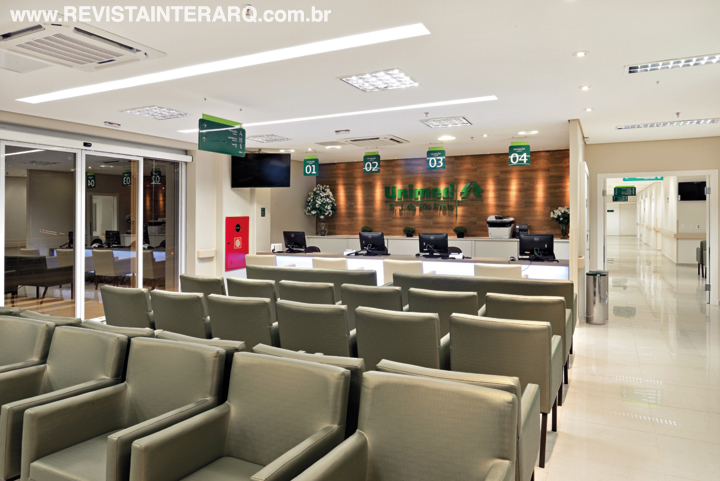 A recepção principal promove a organização e otimização do tempo com o conforto de poltronas estofadas. O balcão de atendimento em acrílico e Caesarstone tem iluminação embutida em Led