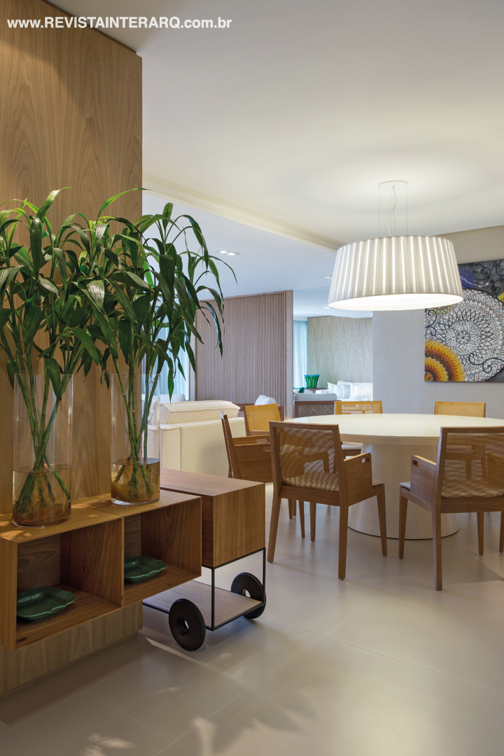 Mesa em laca branca e cadeiras em madeira com encosto em palha natural formam o jantar. O grande pendente, da Kelvin LD, distribui confortavelmente a iluminação