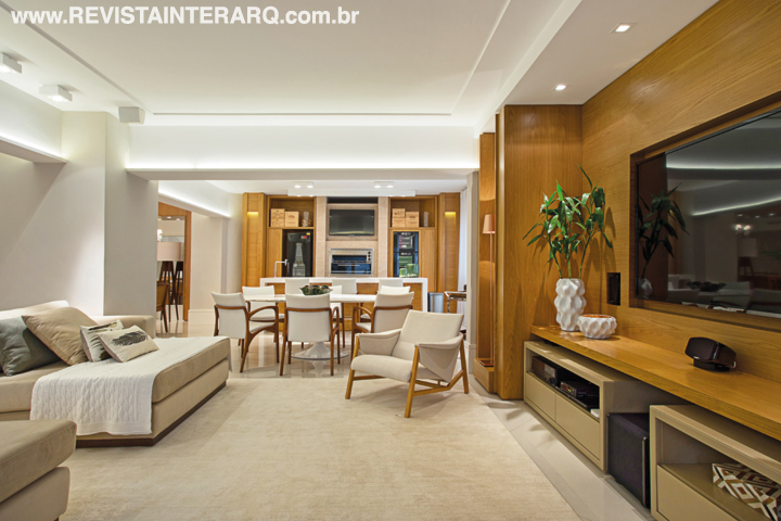 Painéis e nichos em madeira freijó se estendem por todo o apartamento, conferindo unidade visual. A marcenaria foi toda projetada e detalhada pelo escritório e executada pela Móveis RM. No home theater, nichos laterais comportam luminárias de piso em cobre (Kelvin LD) e os armários baixos revestidos em couro pespontado (Le Cadeau Curtume Casa) somam elegância. As poltronas são assinadas por Jader Almeida (Marcia Silveira Ambientações)