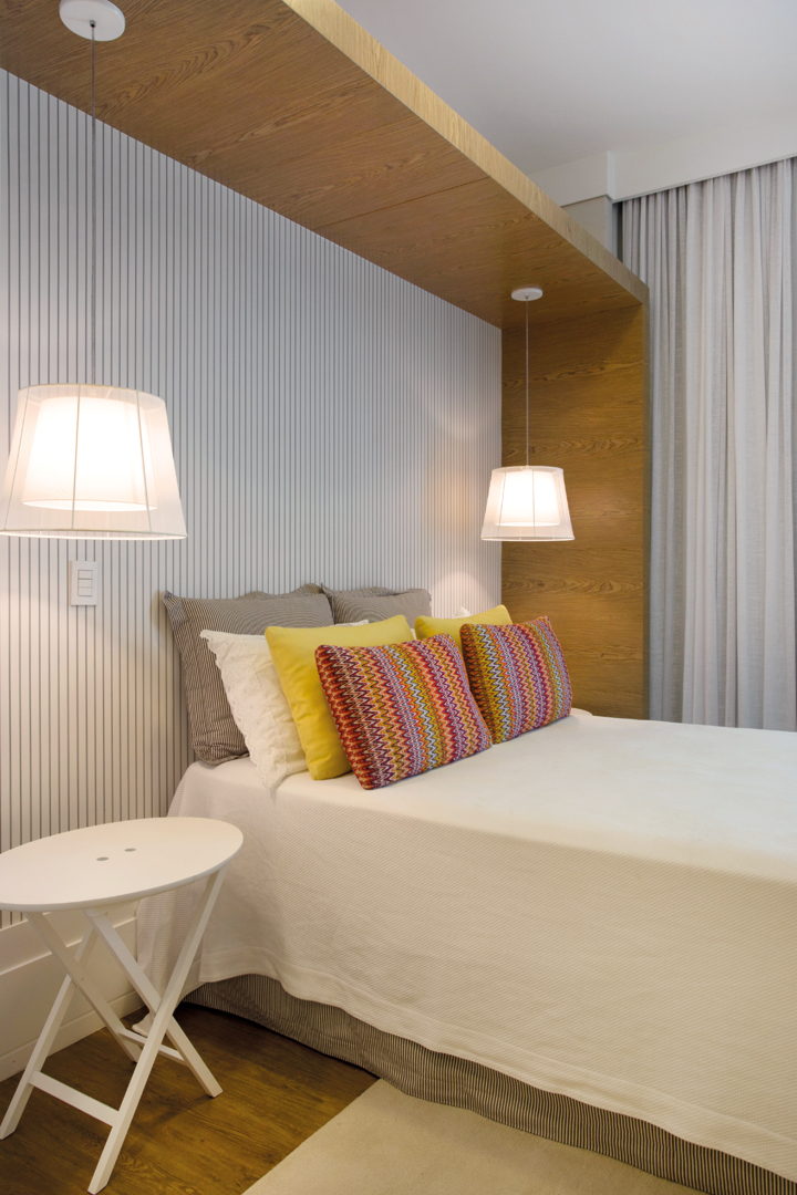 A arquiteta apostou no papel de parede listrado (Délicatesse Tecidos) e moldura de madeira (Incomap Móveis) sustentando os pendentes de tecido (Kelvin LD). Roupa de cama da Bandeirantes Casa com almofadas da Délicatesse Tecidos