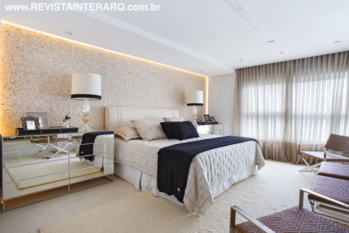 A atmosfera relaxante da suíte mescla espelhos, enxoval claro e parede com mosaico de mármore emoldurado por uma sanca de gesso iluminada (Gessoteto)