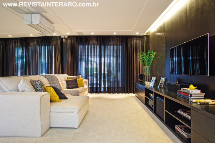 Móveis em madeira ebanizada, cortinas pretas e painéis em pastilhas de vidro escuras (Portobello Shop) fazem contraponto ao tapete e sofá crus do home theater. O forro de gesso com sanca foi executado pela Gessoteto