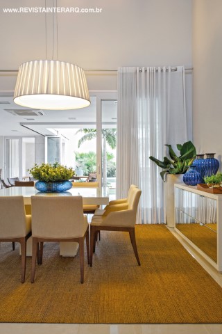 A sala de jantar, com tapete em sisal natural, cadeiras revestidas (Marcia Silveira Ambientações) em linho e pendente Bertolucci da Kelvin LD. Toda em mármore Branco Piguês (Marmoraria Gran-Norte), a escada de acesso à ala íntima dá continuidade visual ao piso em porcelanato da Portobello Shop