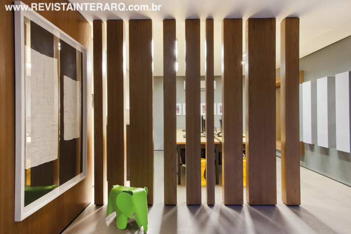 A fluidez dos ambientes setorizados por pilares de Carvalho de diferentes espessuras. O piso de todo o escritório foi revestido com porcelanato que remete às pedras naturais. A banqueta Elephant é uma obra de Charles Eames