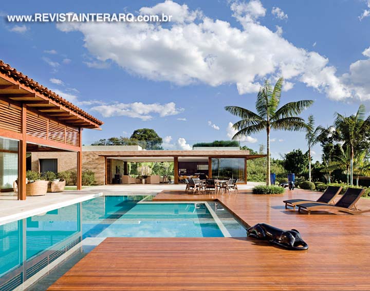 Revestida com pastilhas azuis, a piscina de frente para a área social da casa integra, junto com o deck em Ipê, o novo pavilhão, que traz um conceito mais limpo, com linhas retas e visualmente unificado aos jardins (paisagismo de Ana Paula Roseo). A proposta arquitetônica com laje plana viabilizou a criação de uma área superior com lareira e um SPA aberto, com guarda-corpo de vidro e toda a vista maravilhosa que o terreno proporciona