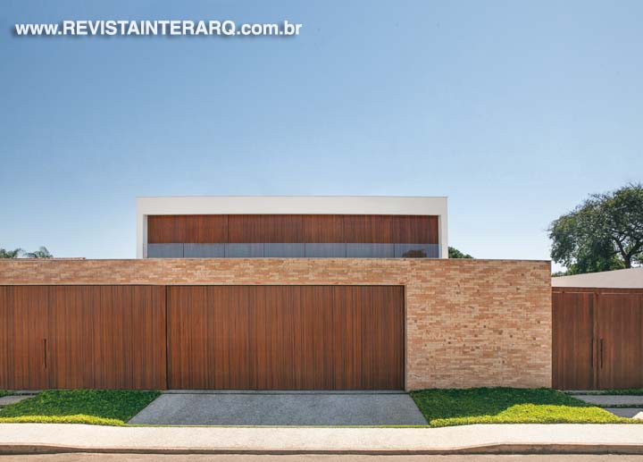 O mesmo fechamento em madeira cumaru na garagem e no pavimento superior ressalta a arquitetura de linhas puras e o aconchego dos tijolos à vista. O guarda-corpo de vidro faz sua função sem interferir no jogo de volumes