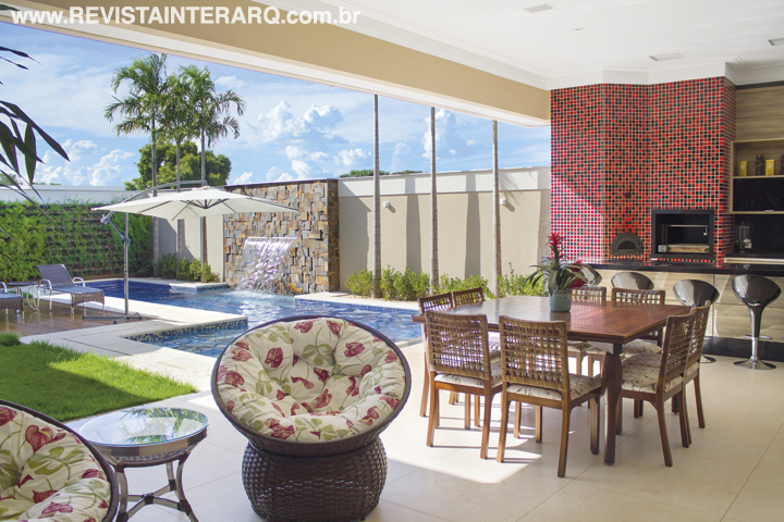 A varanda tem a energia da parede revestida com pastilhas vermelhas e pretas. A mesa é assinada pelo designer de Márcio Colaferro